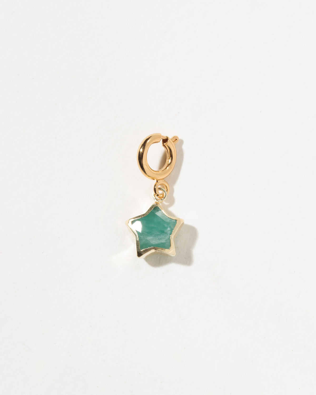 Gold charm with a green star-shaped gem on a white background