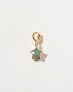 Gold star-shaped pendant with a green stone on a light gray background