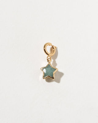 Gold star-shaped pendant with a green stone on a light gray background