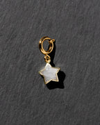 Gold star-shaped charm with a white stone on a dark gray background