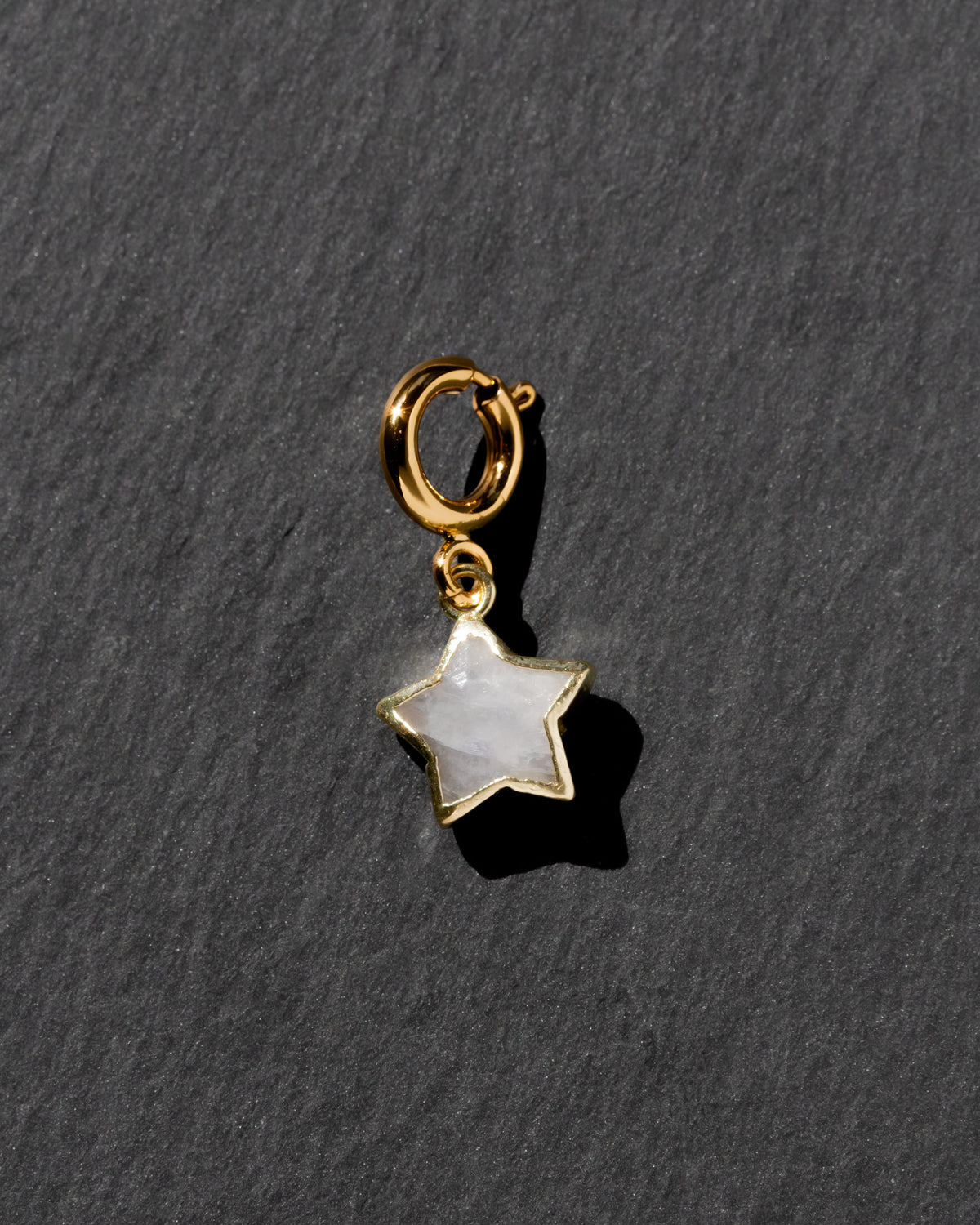 Gold star-shaped charm with a white stone on a dark gray background