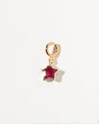 Gold charm with a ruby gemstone on a white background
