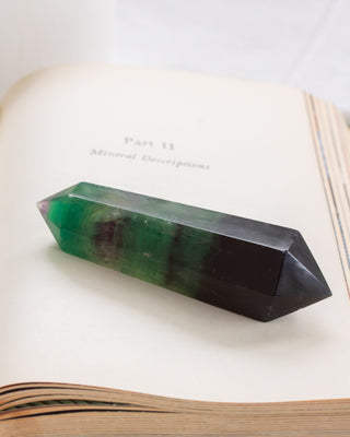 Crystal wand with green and purple colors on an open book