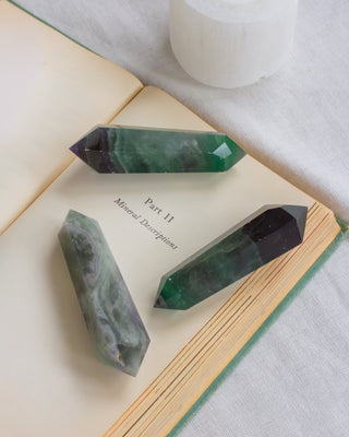 Crystal points on an open book with a white candle in the background