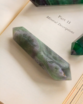 Green crystal on an open book with text about mineral descriptions