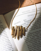 Rainy Day necklace in Gold, laying on a book.