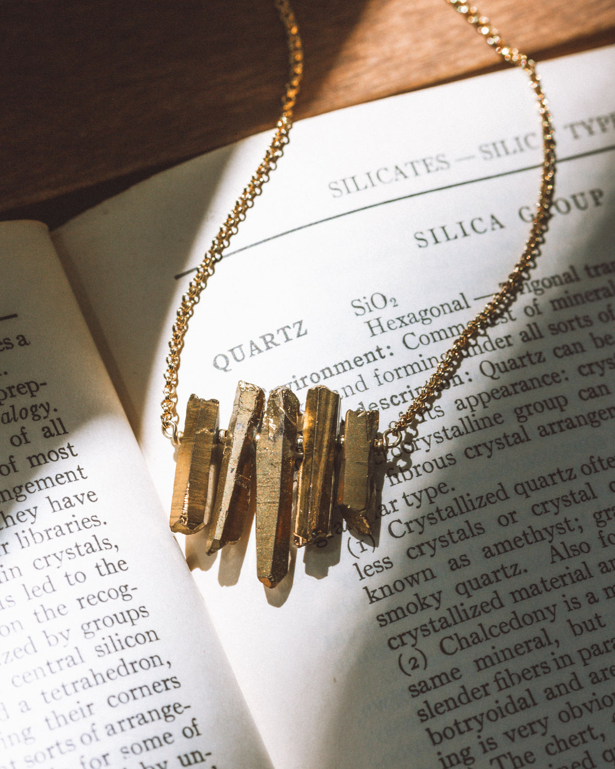 Rainy Day necklace in Gold, laying on a book.