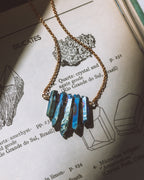 Necklace with metallic blue and green gemstones on a book page with mineral illustrations