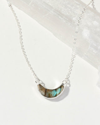 Silver necklace with a green labradorite stone pendant on a white background