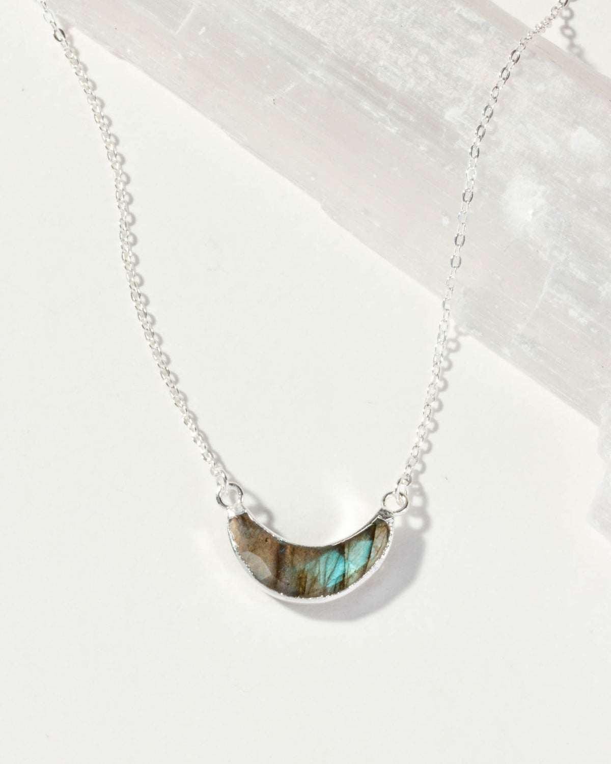 Silver necklace with a green labradorite stone pendant on a white background