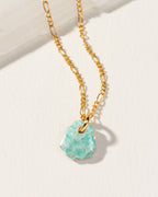 Gold necklace with a mint amazonite pendant on a light background