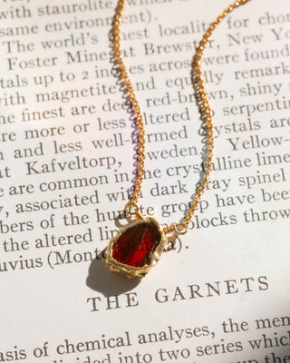 red stone gold chain necklace on book