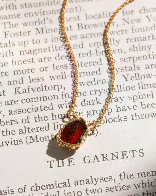 red stone gold chain necklace on book