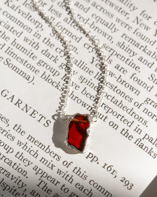 Red stone silver necklace on a book page