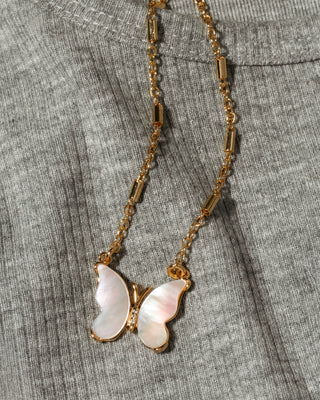A gold chain necklace with a butterfly pendant made of iridescent mother-of-pearl wings.