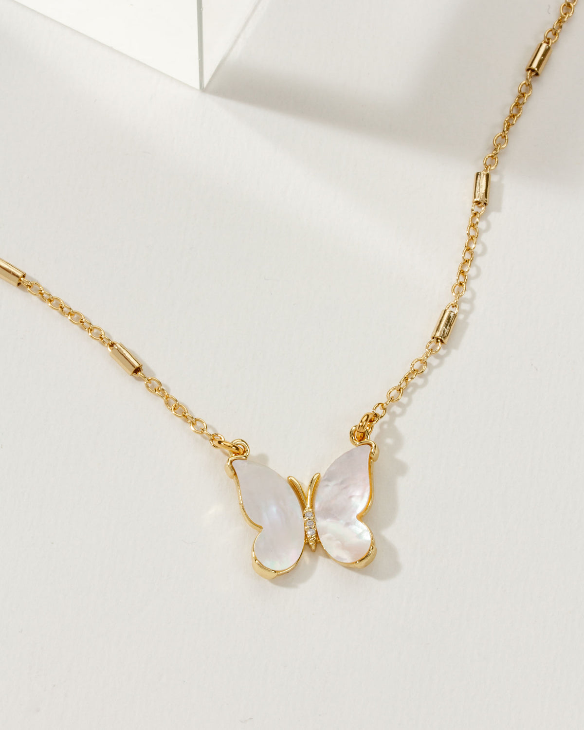 Gold necklace with a butterfly pendant on a white background