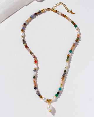 A beaded necklace with a mix of colorful stone beads, white pearl-like beads, and gold-toned spacer accents, featuring a dangling white pearl.