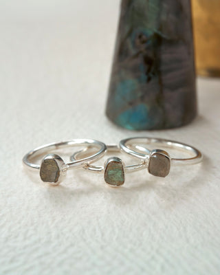 Three silver rings, each with labradorite gemstones displayed on a white surface.
