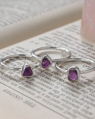 Three silver rings with purple amethyst gemstones on an open book