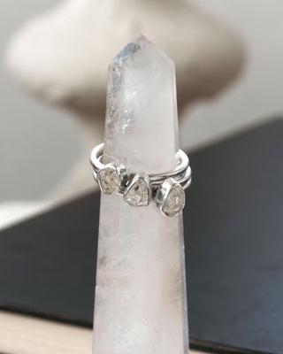 Three stacked silver rings with herkimer quartz gemstones displayed on a crystal tower.