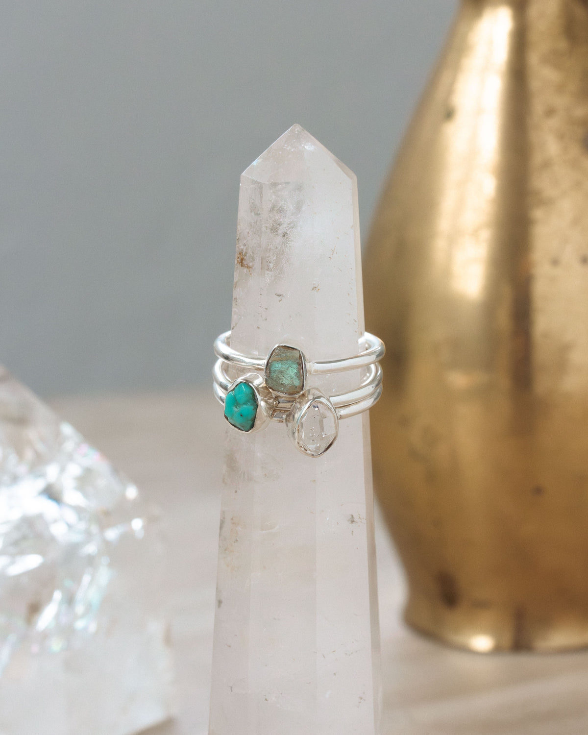 Turquoise, Herkimer quartz, and labradorite silver rings on a crystal tower