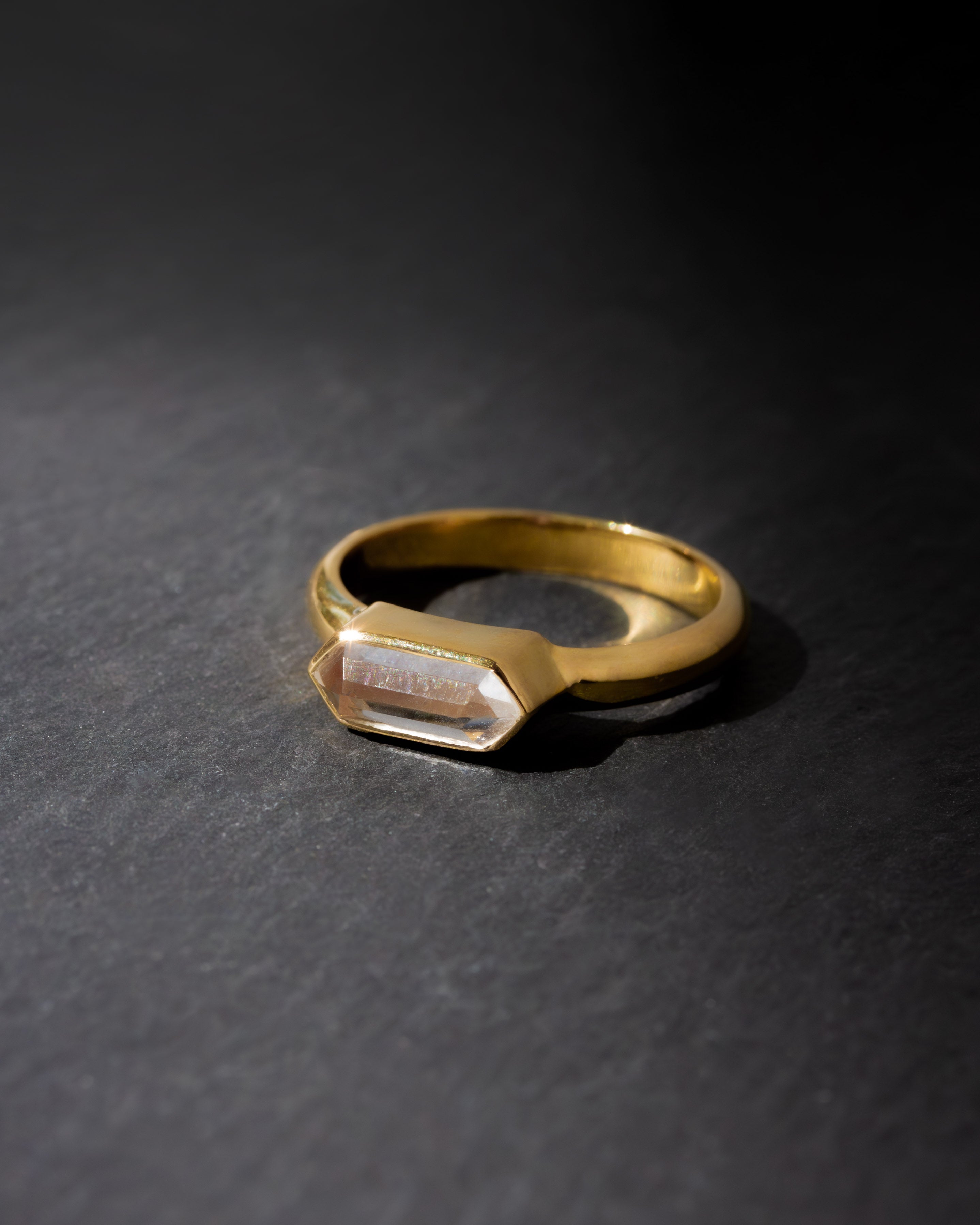 Gold ring with a rectangular gemstone on a dark gray background
