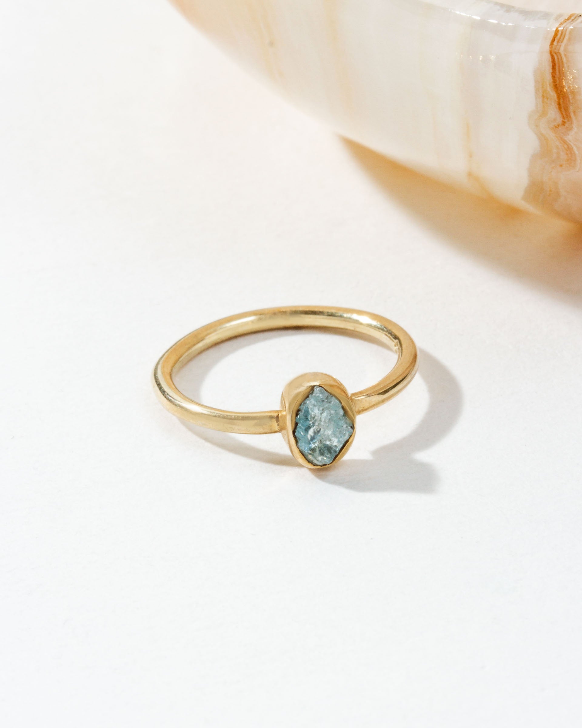 Gold ring featuring a blue Aquamarine gemstone on a white surface.