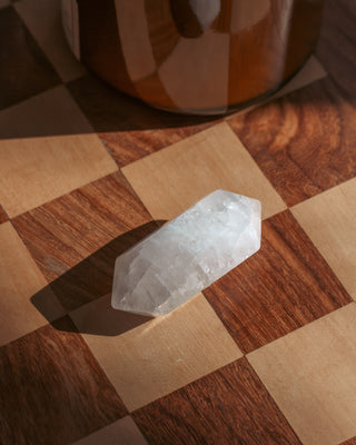 White double point quartz crystal on a wooden checkerboard surface