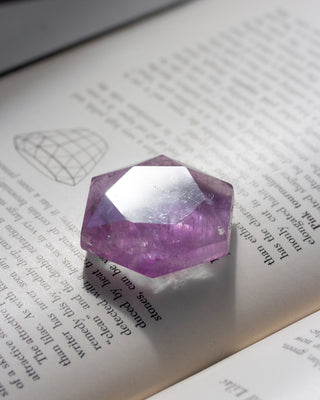 Faceted amethyst crystal on an open book