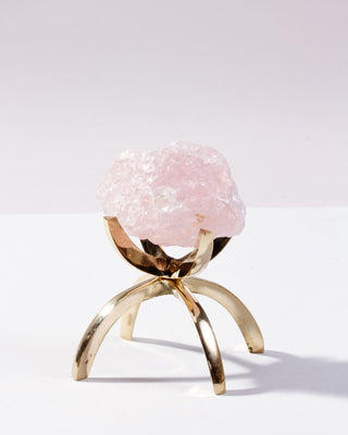 Decorative object with pink crystal on a gold stand against a white background