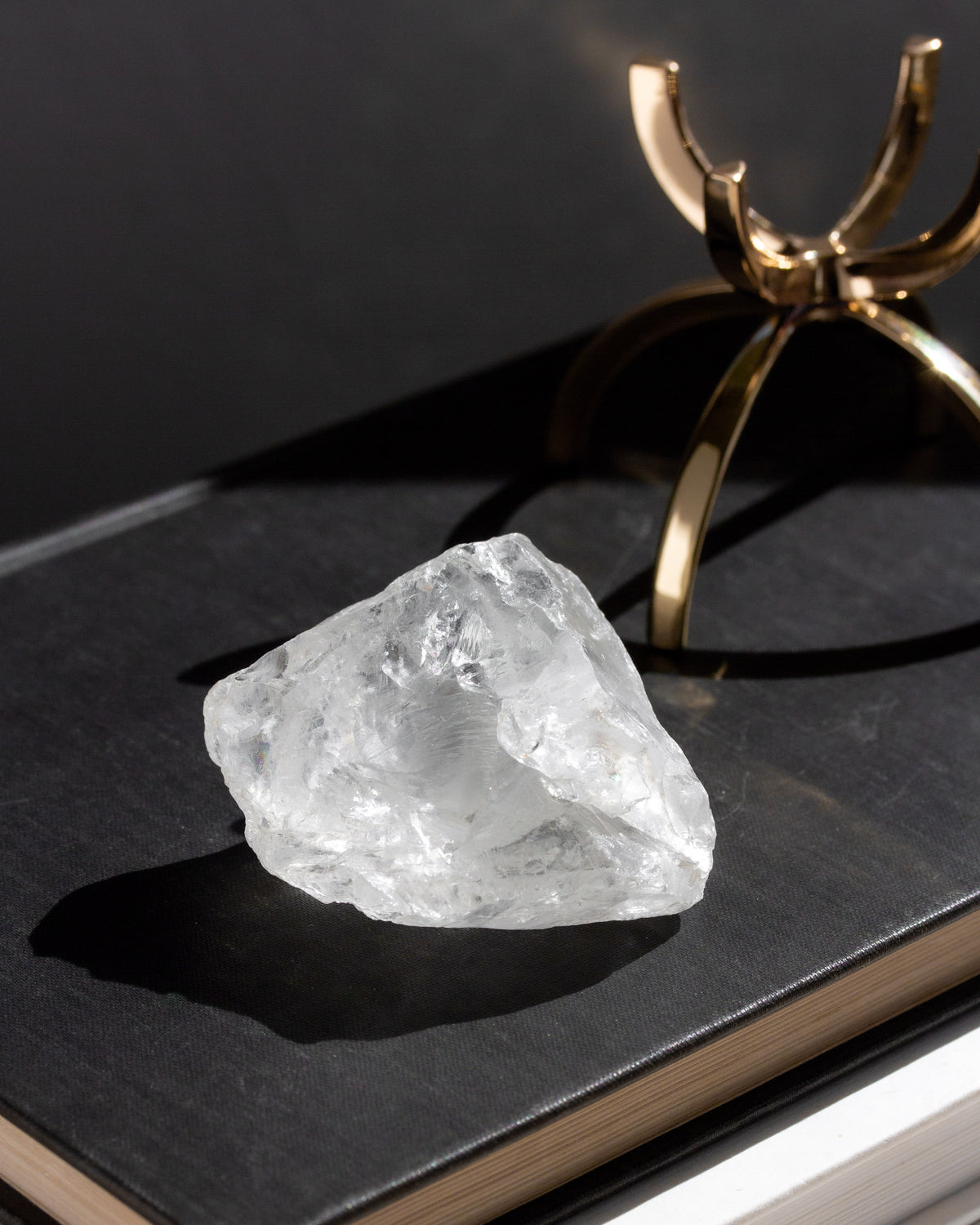 Raw quartz rock on a black surface with a gold decorative object in the background