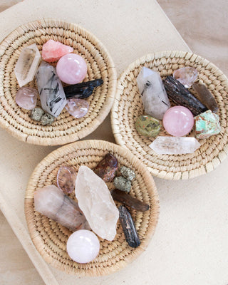 Three baskets full of a variety of rough and cut crystals.