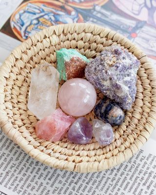Multi pastel genuine gemstone crystal set placed in a natural color woven basket placed on top of a book for decoration