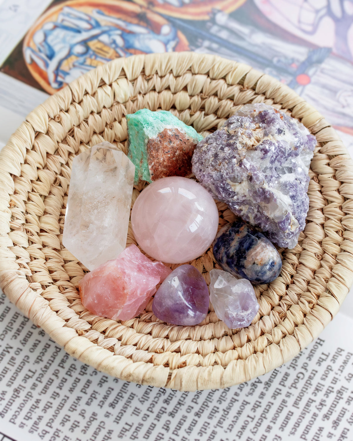 Multi pastel gemstone crystal set placed in a natural color woven basket on a book