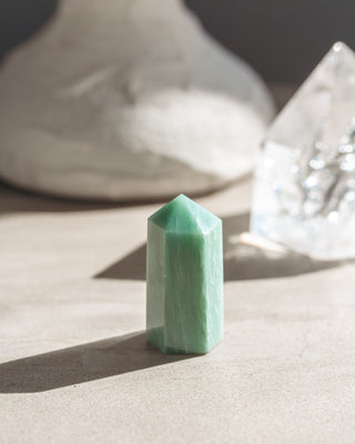 Green amazonite crystal mini tower on a neutral surface with soft focus background