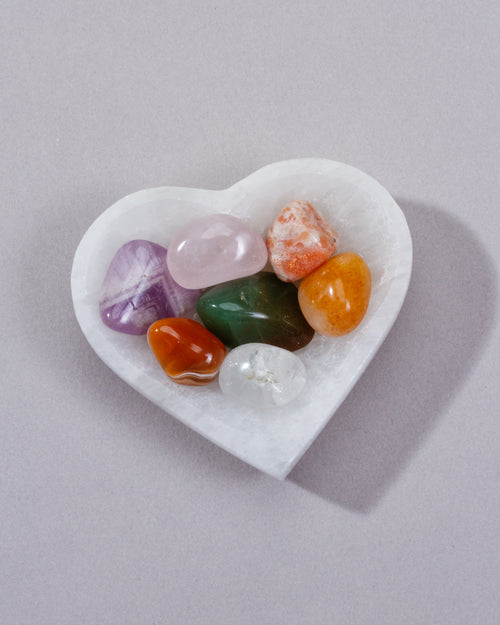Heart-shaped white stone with colorful crystals on a gray background