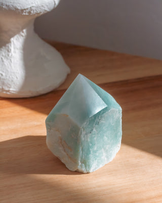 Crystal-like object on a wooden surface with a white pedestal in the background