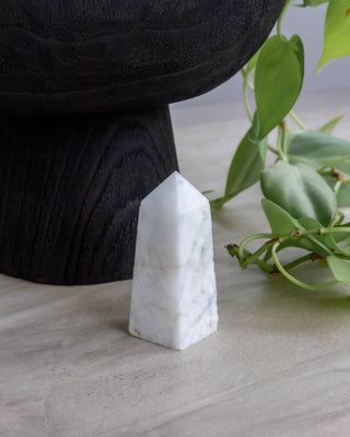 White stone pyramid on a light surface with green leaves in the background