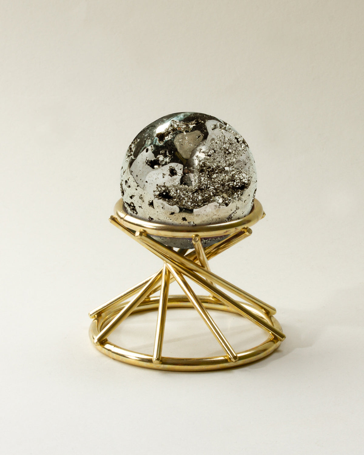 Pyrite sphere with natural inclusions on a gold stand.