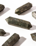 Several Golden Balance Pyrite Double Point Mini Crystals are displayed on a white surface.
