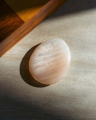 Smooth beige Peach Aventurine stones on a textured surface
