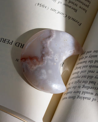 Close-up of a textured moon carved stone on an open book