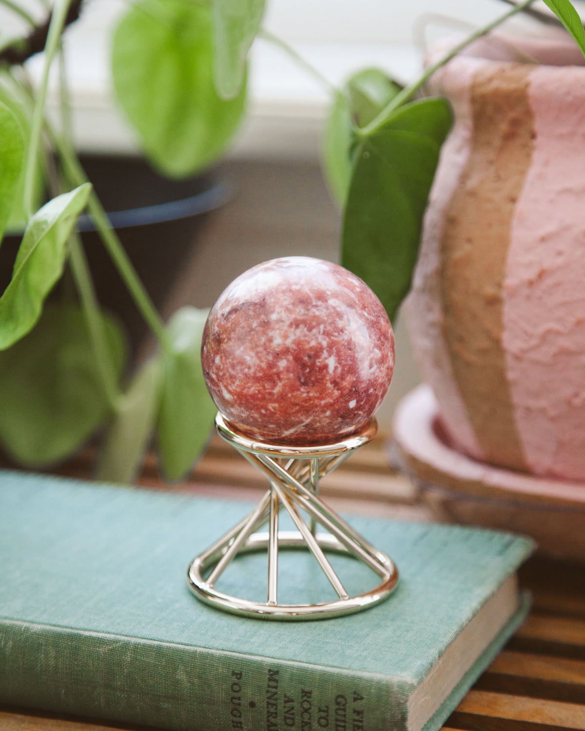 Pink Calcite sphere on a gold stand.