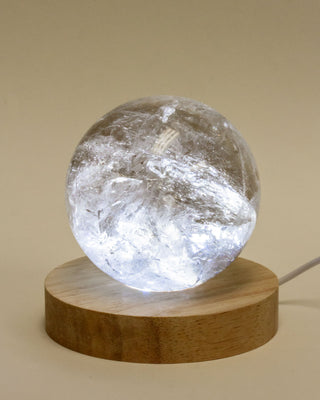 Crystal ball light on a wooden base against a beige background