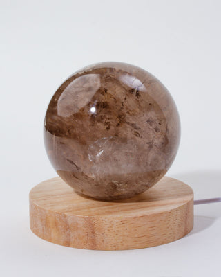 Brown crystal sphere on a wooden base with a white background