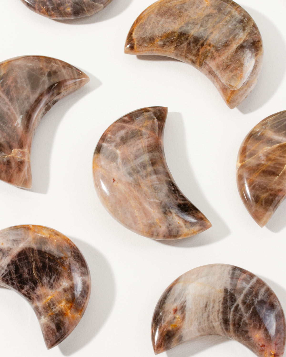 Waxing Crescent Brown Moonstone Gemstone curios, arranged on a white surface.