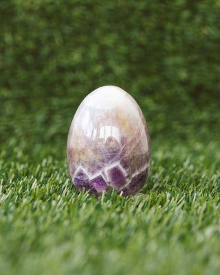 Polished amethyst stone on grass with a blurred green background