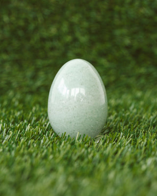 Green gemstone egg on a green grass background