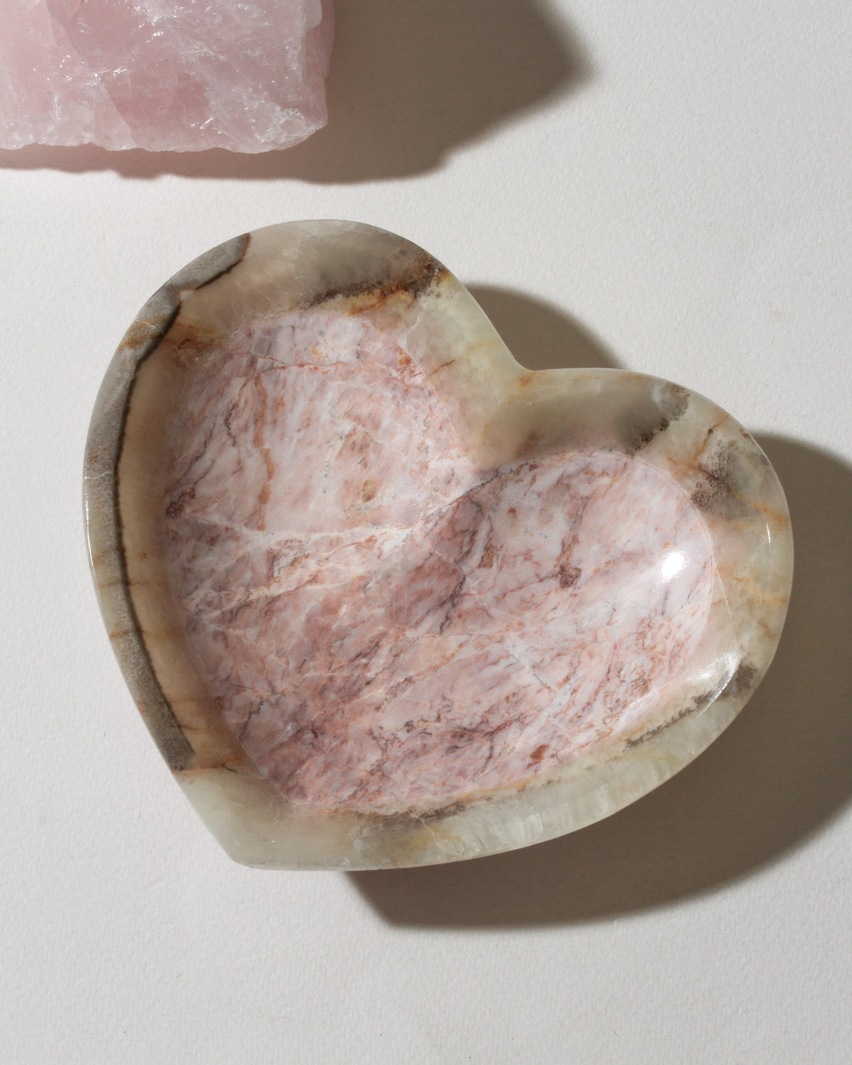 Heart-shaped stone with pink and brown hues on a light background