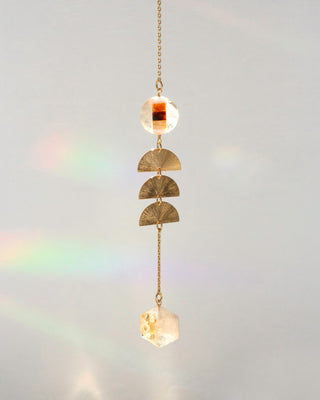 A gold-toned hanging ornament with three textured gold semicircle discs, and a citrine faceted crystal pendant.